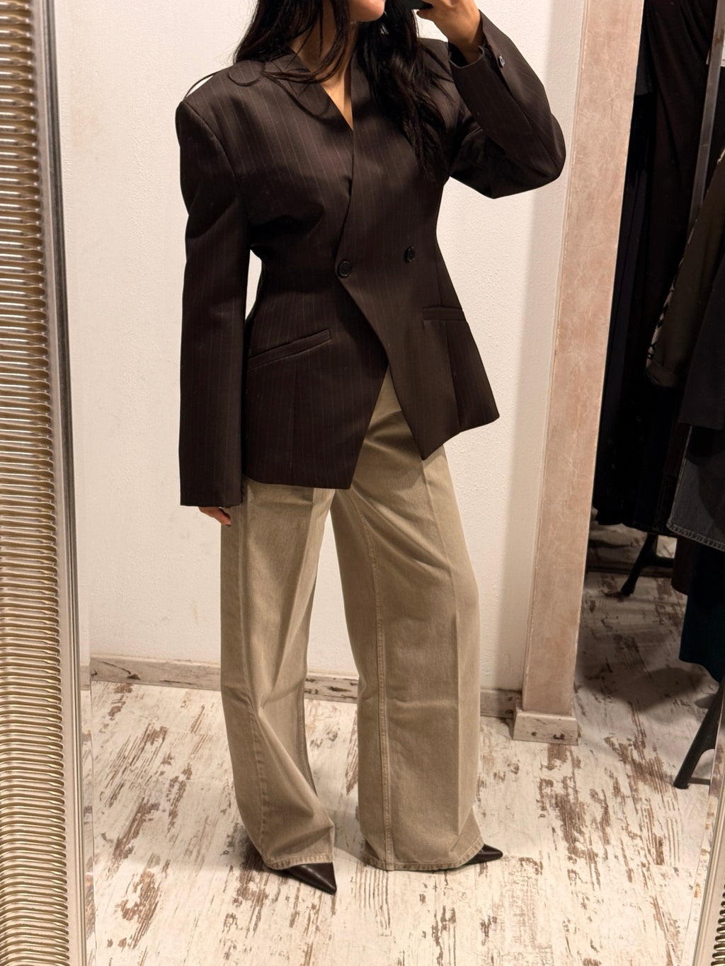 Blazer scuro con bottoni e tasche a patta, linea sagomata sul busto.