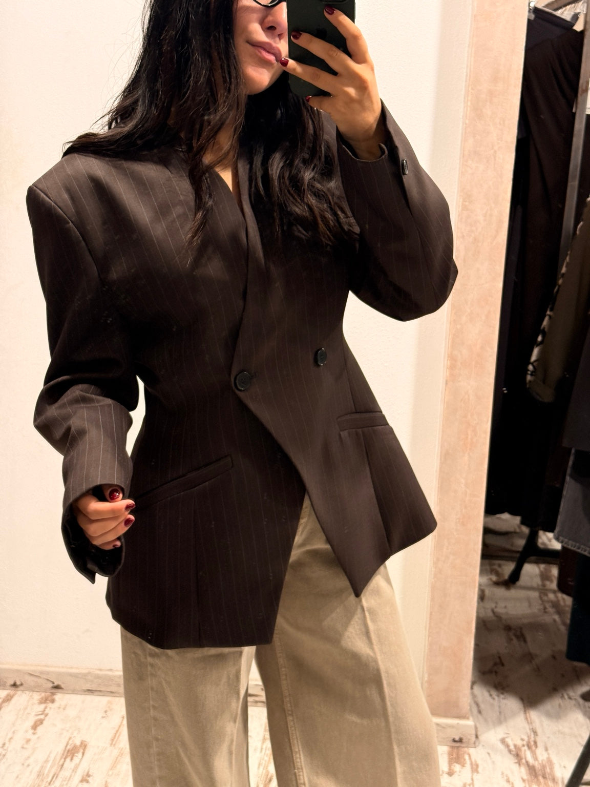 Blazer scuro con bottoni frontali, tasche a pattina e spacco laterale.