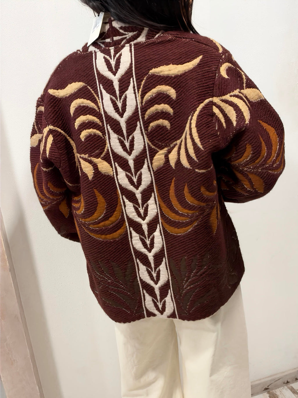 Cardigan jacquard marrone con motivo foglie e ricami beige sul dorso.